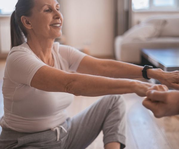 A smiling woman sitting comfortably on a yoga mat after a practice session.