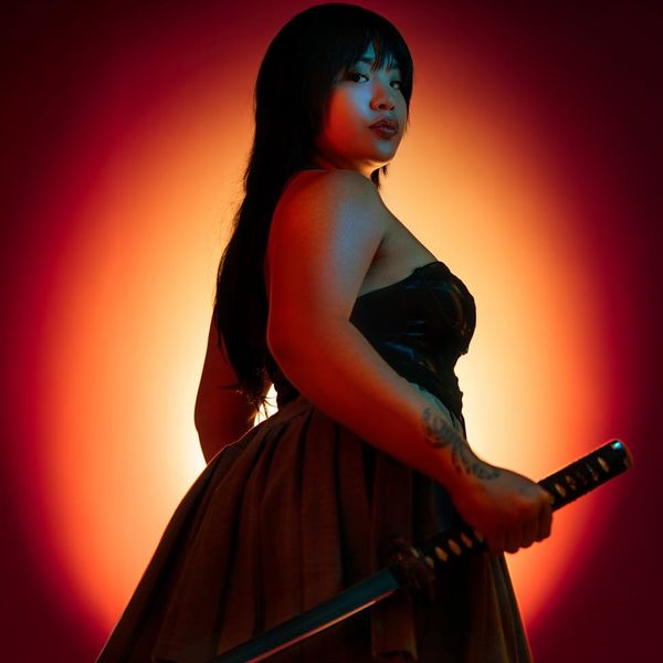 Silhouette of a woman in a powerful warrior yoga pose against a dark background.